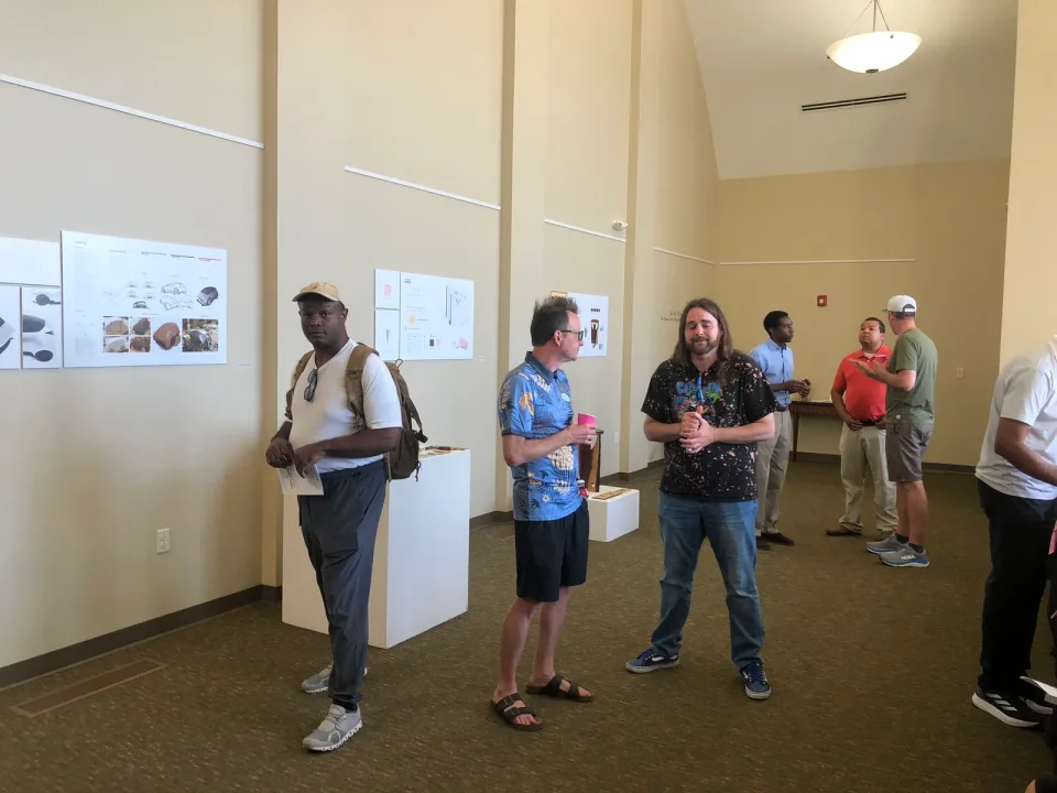Visitors talking beside artwork and display panels at the Foster Gallery show.