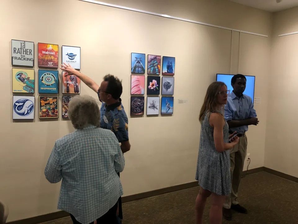 Visitors looking closely at a grid of poster-like artworks at Foster Gallery.