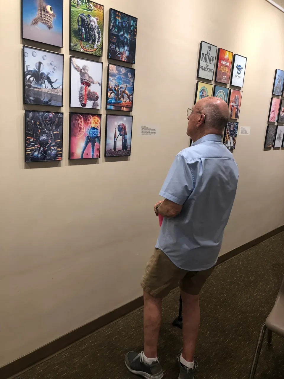 A visitor studying two groups of framed artworks on the gallery wall.