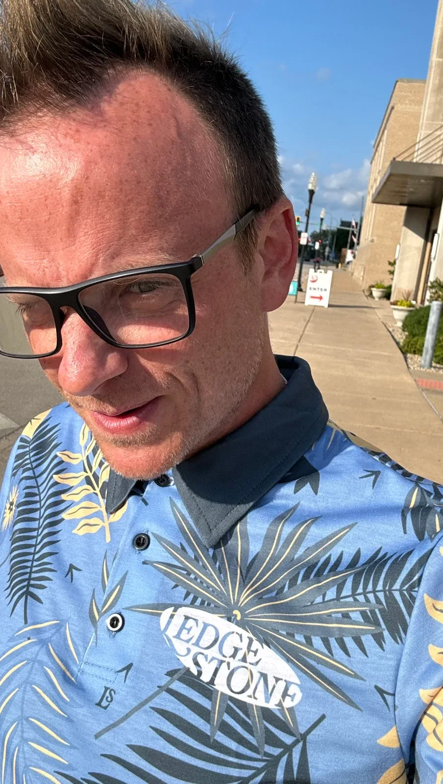 An outdoor portrait of a person wearing glasses and a blue patterned shirt, from the Foster Gallery show archive.